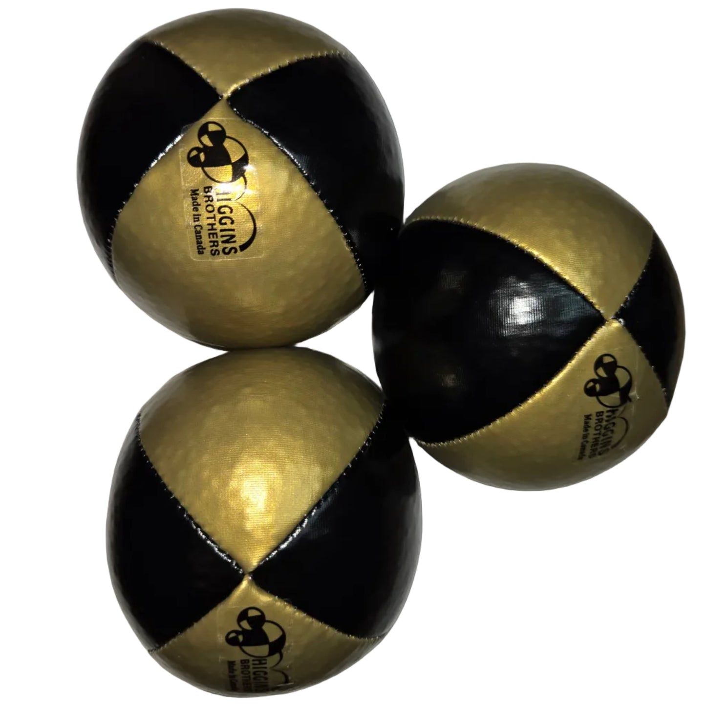 Three gold and black juggling balls resting on a white surfe