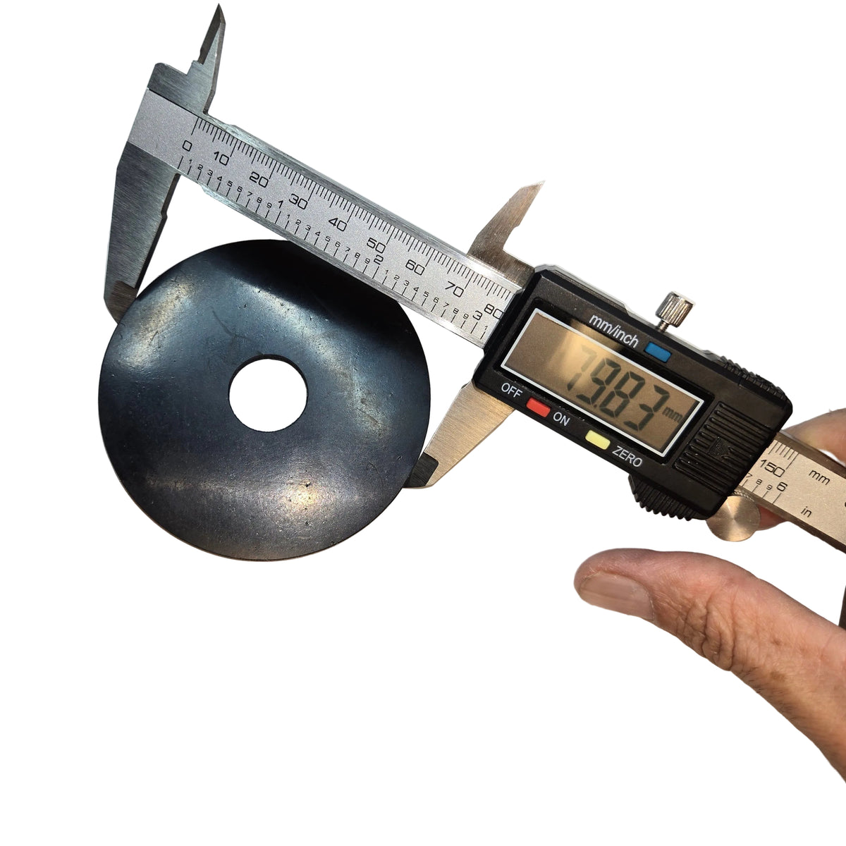 A black circular disc with a central hole being measured with a digital caliper on a white sheet of paper, with a hand holding the caliper.